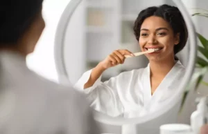 femme qui se brosse les dents devant un miroir