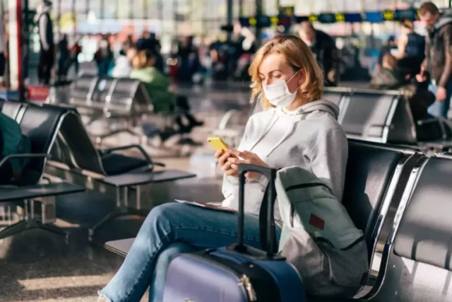 femme assises dans un aéroport avec un masque